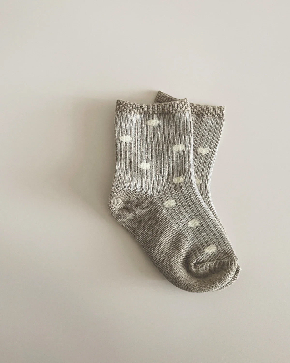 The SUSUKOSHI Socks Dots are displayed on a neutral background. These stylish, unisex grey ribbed socks with white polka dots are made from a soft cotton blend and are neatly arranged side by side with their cuffs overlapping slightly.