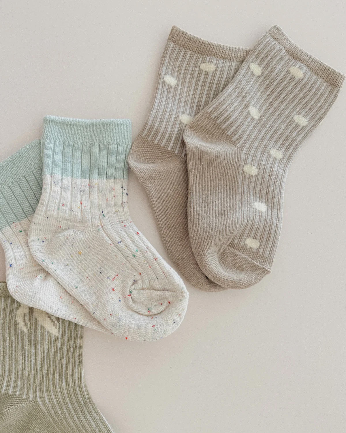 Three pairs of SUSUKOSHI's Socks Dots are displayed against a white background. One pair is light green, the second pair is white with colored specks, and the third pair is beige with white polka dots. All socks have a ribbed texture and are made from a comfortable cotton blend.