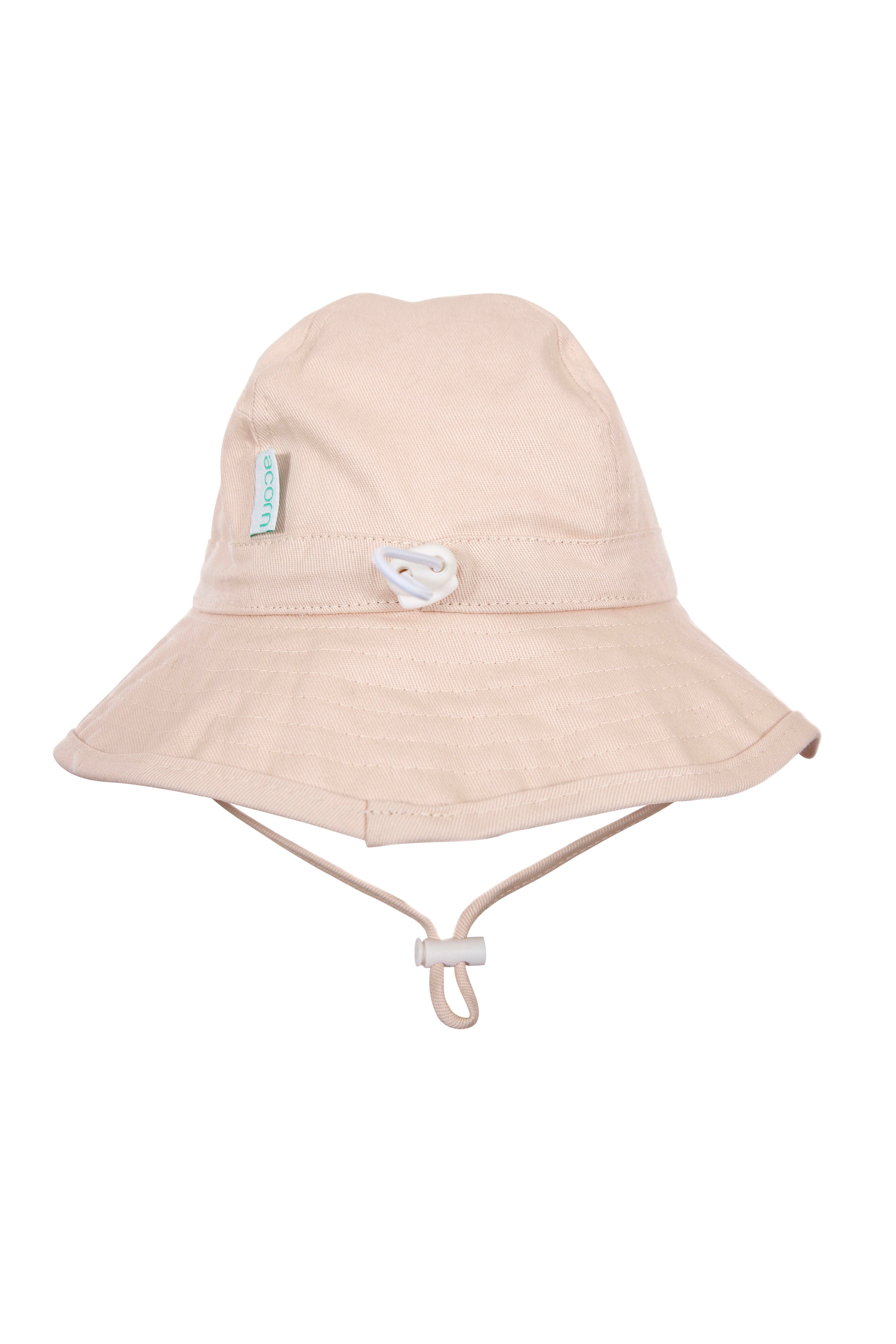 The Wide Brim Infant Hat Vanilla by ACORN KIDS is a beige bucket hat featuring a wide brim, adjustable chin strap, and a small green tag on the side. Made from light, durable cotton canvas, it offers UPF50+ sun protection. Its casual design is ideal for outdoor activities for both adults and infants alike.