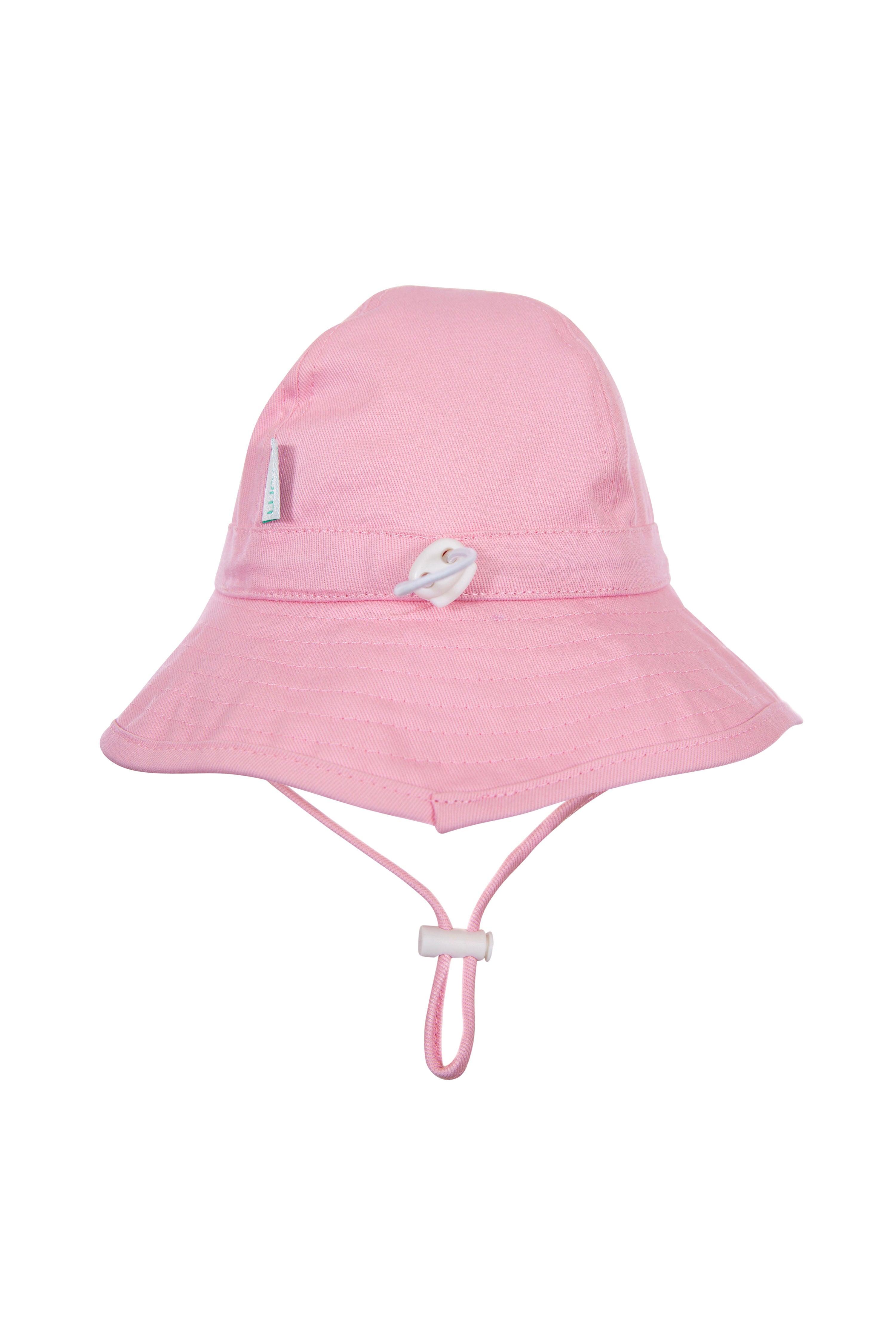 The ACORN KIDS Wide Brim Infant Hat Pink is a light pink bucket hat made from cotton canvas, featuring a wide brim for sun protection and an adjustable chin strap. This stylish infant hat also includes a small decorative button on the front and stitching details around the brim and crown.