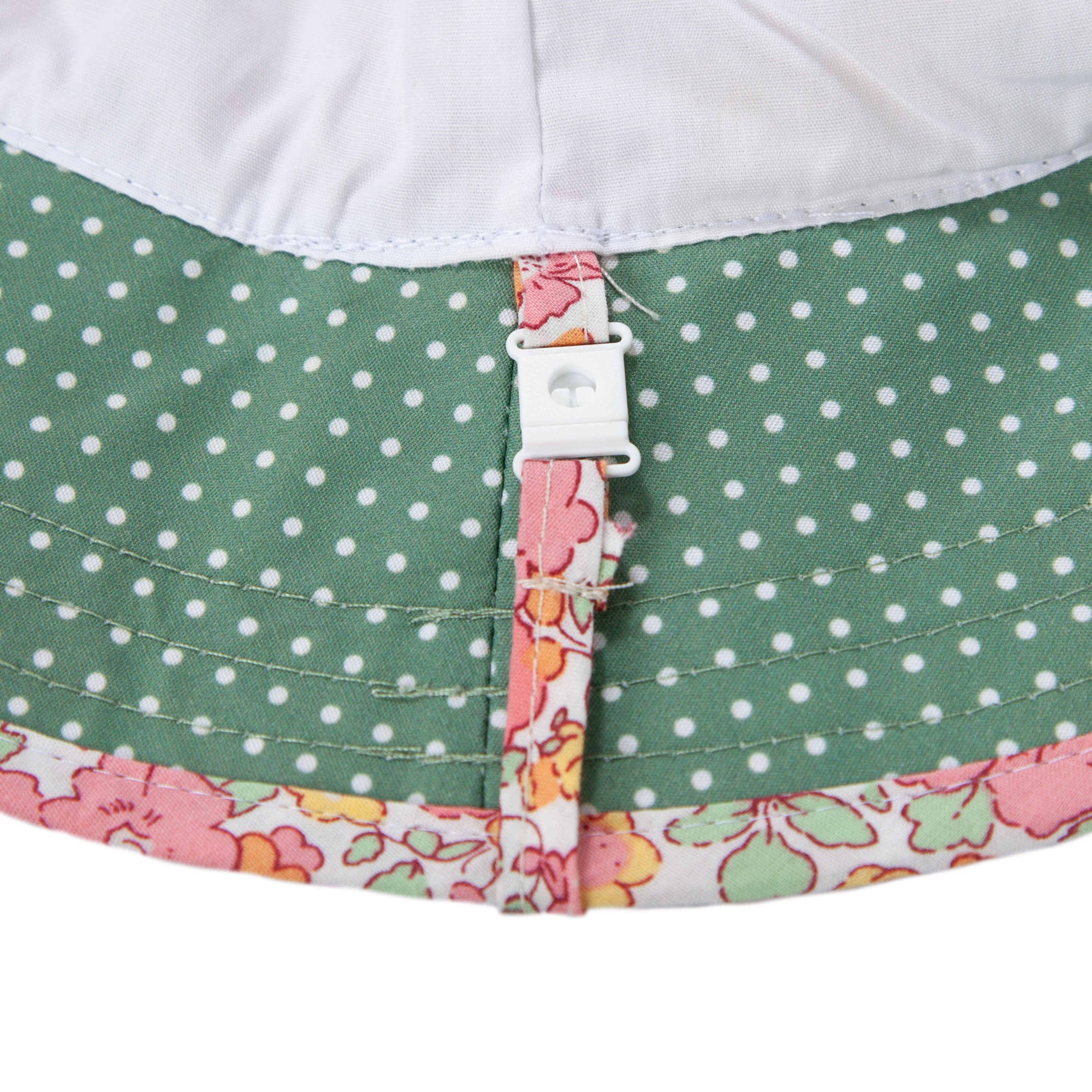 The Acorn Kids - Tessa Broad Brim Bucket Hat by ACORN KIDS features a pink floral design with green and white polka dots, UPF50+ sun protection, and a white plastic toggle on the brim for adjustable fit.