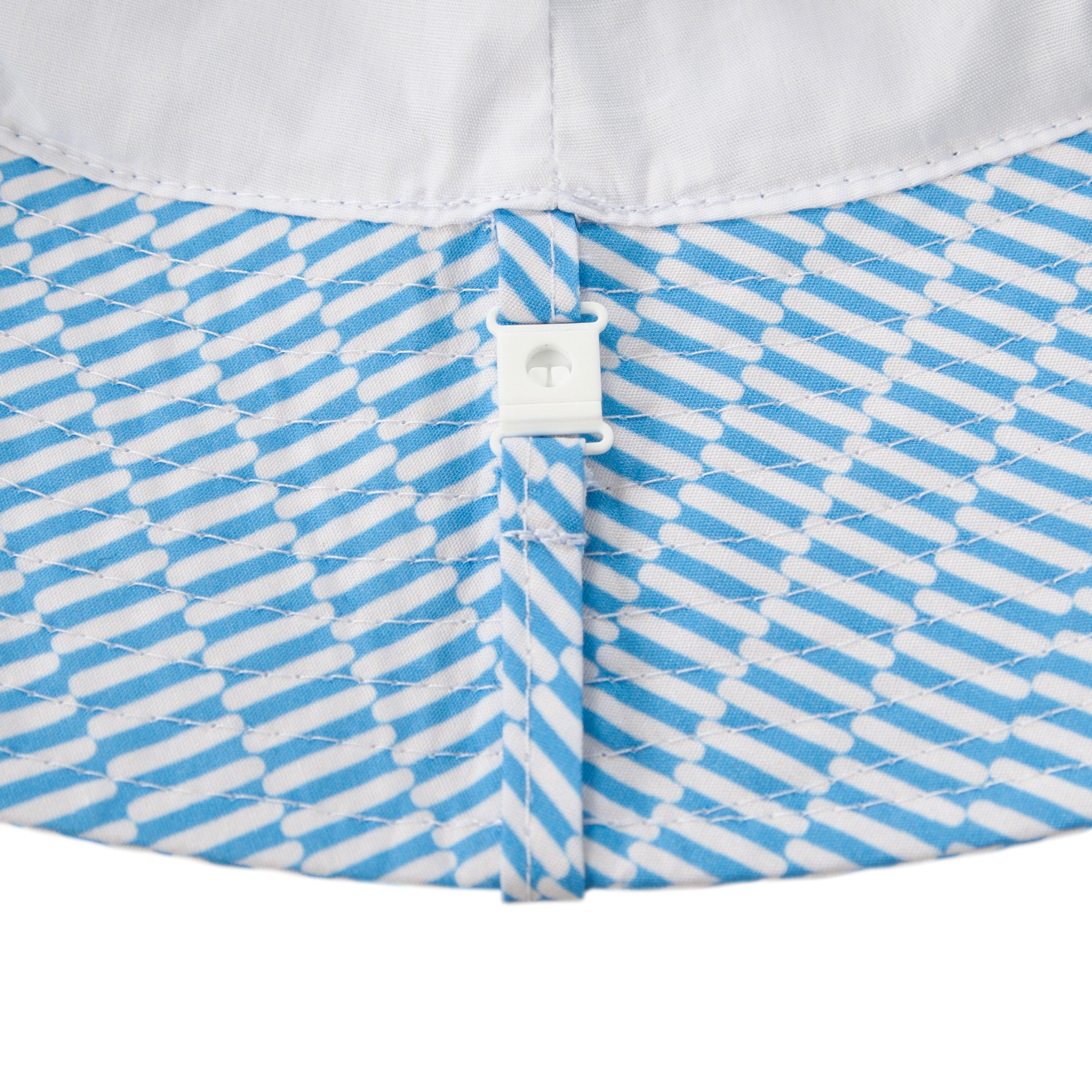 Close-up of blue and white patterned fabric with diagonal stripes and a white snap button—featured on the ACORN KIDS Acorn Kids - Mykonos Wide Brim Bucket Hat, made from 100% cotton with UPF50+ sun protection.