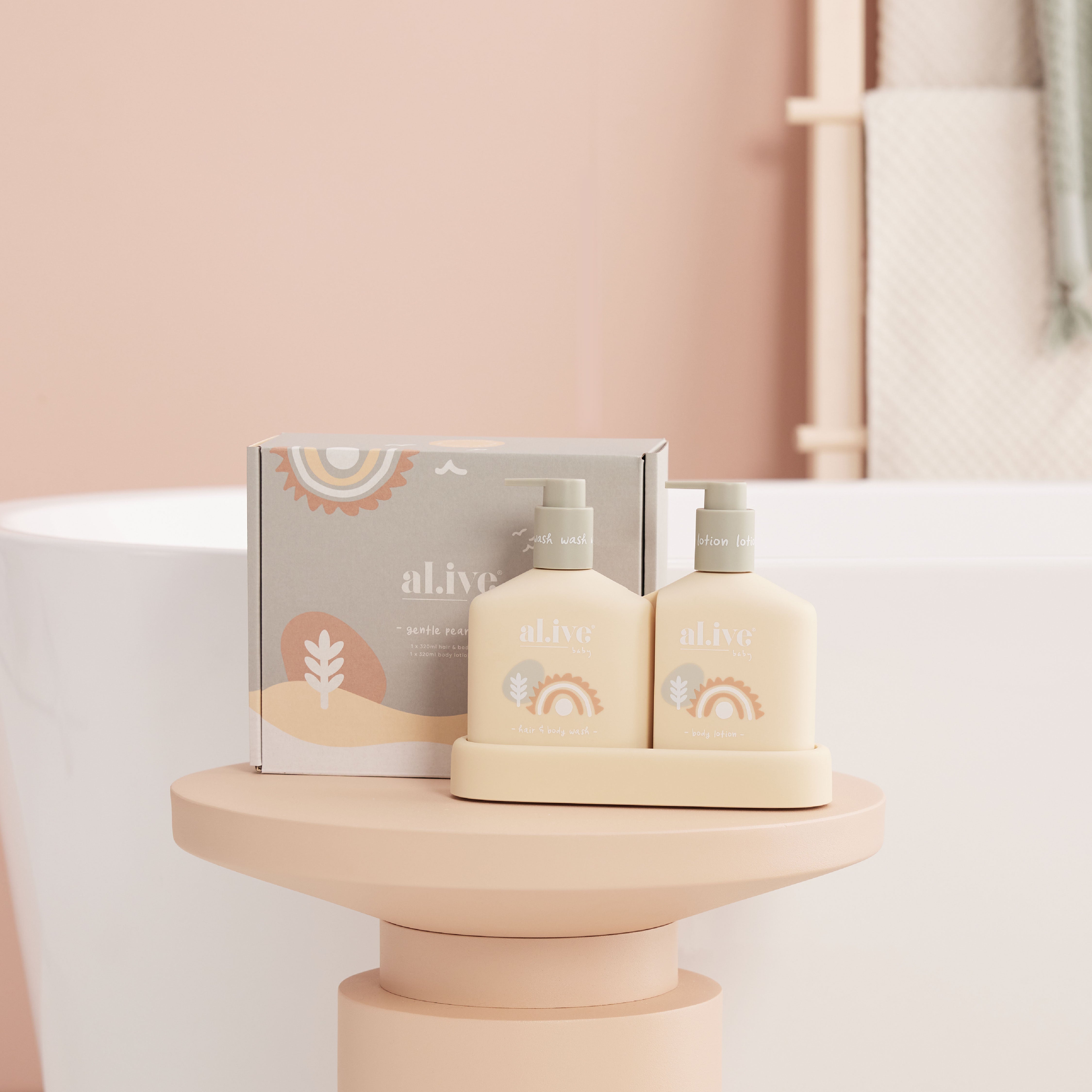 The al.ive hair and body duo gentle pair bottles and cardboard packaging on a rose gold podium with a bath in the background.