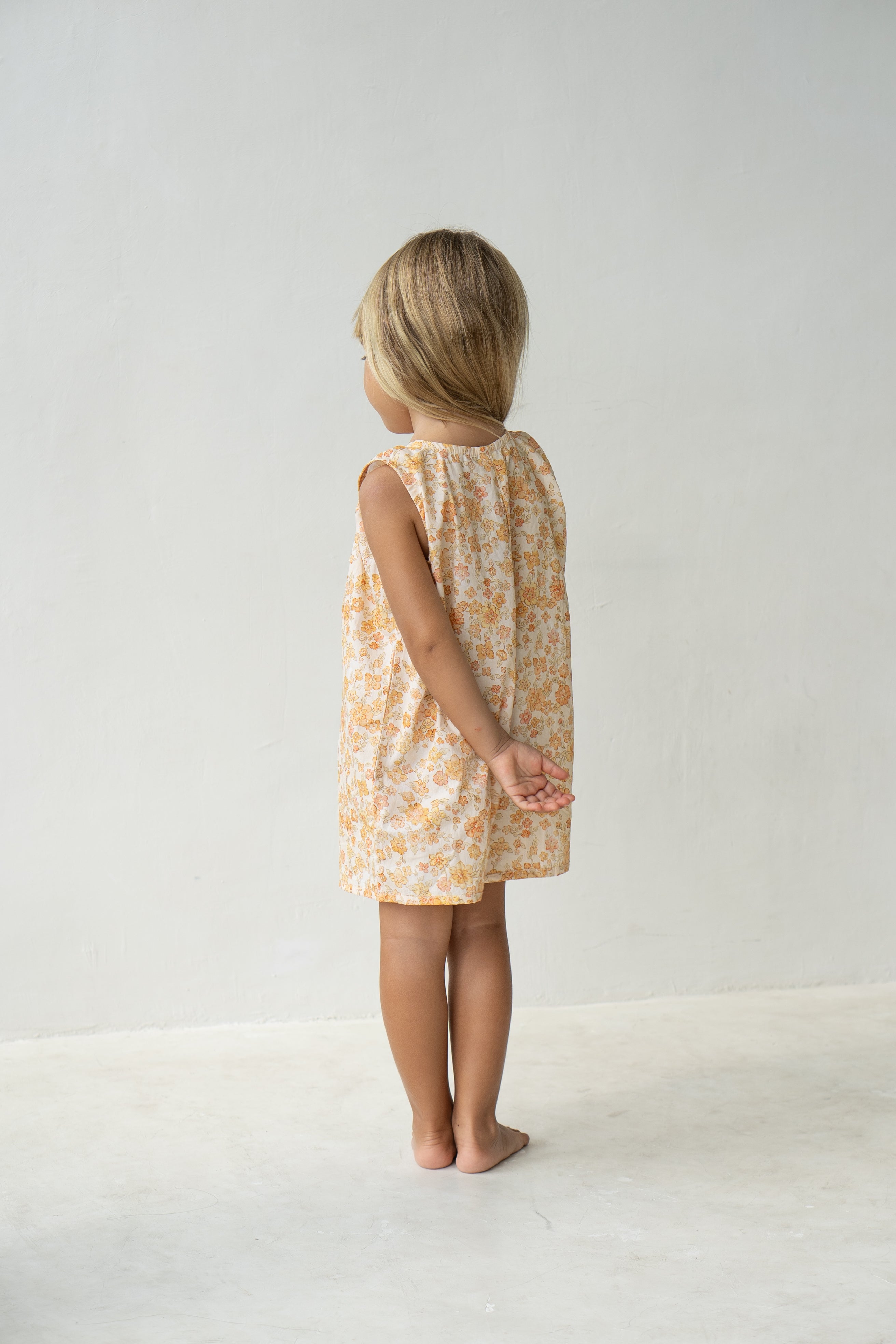 Young girl wearing the Sadie overalls in buttercup.