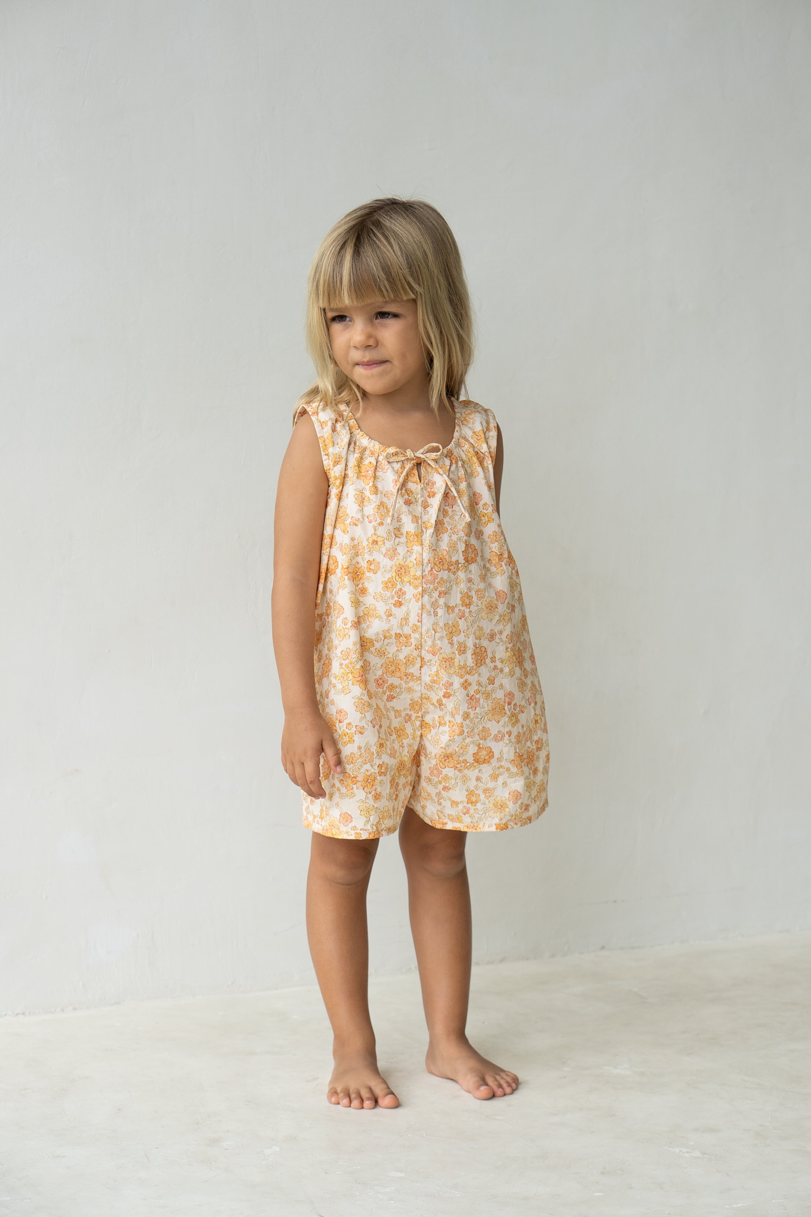 Young girl wearing the Sadie overalls in buttercup.