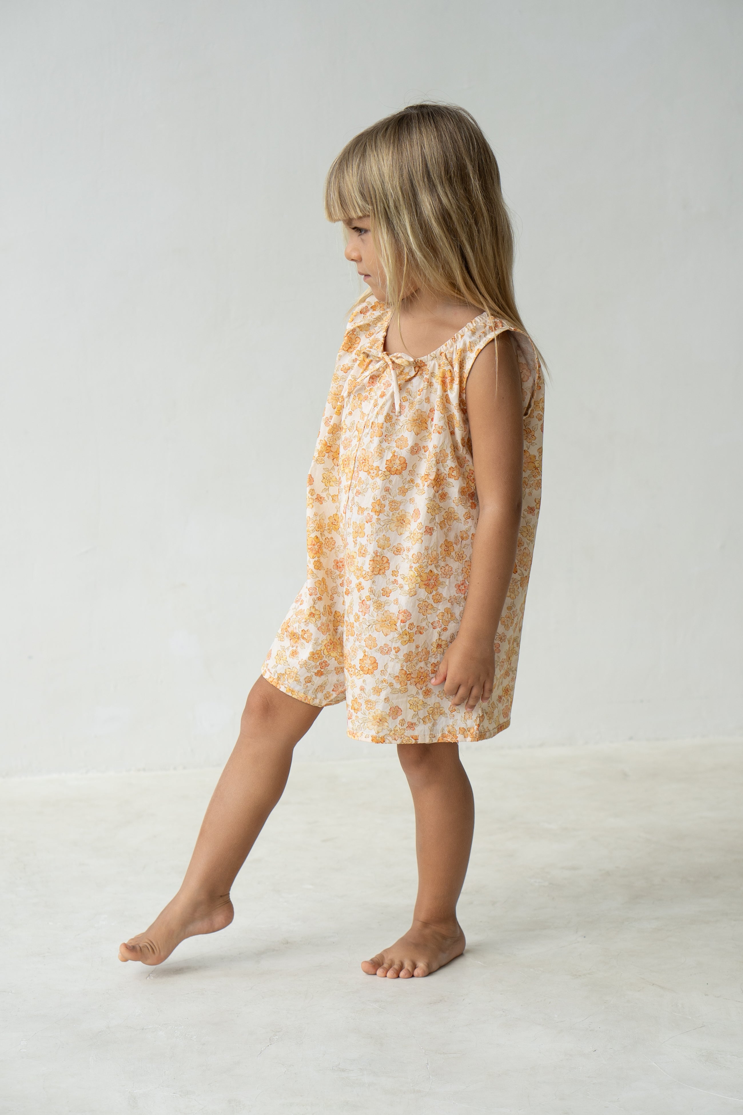 Young girl wearing the Sadie overalls in buttercup.