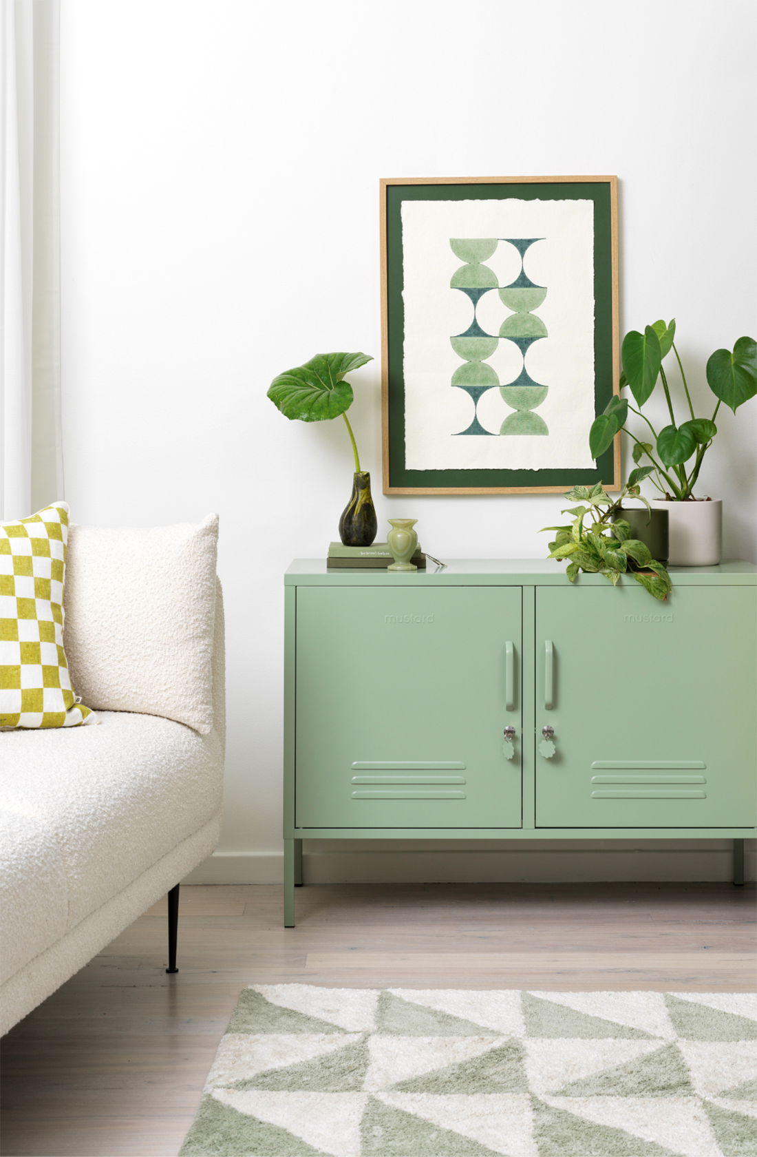 The lowdown locker in sage in a living room with plants on top..