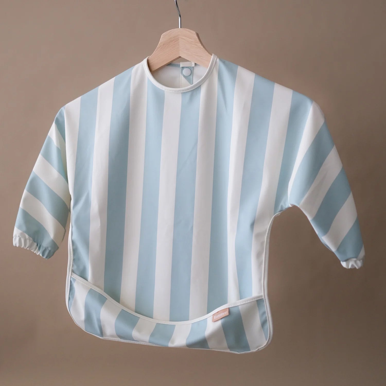 ROMMER Smock Bib in Sea Mist Stripe hanging from a coat hanger.