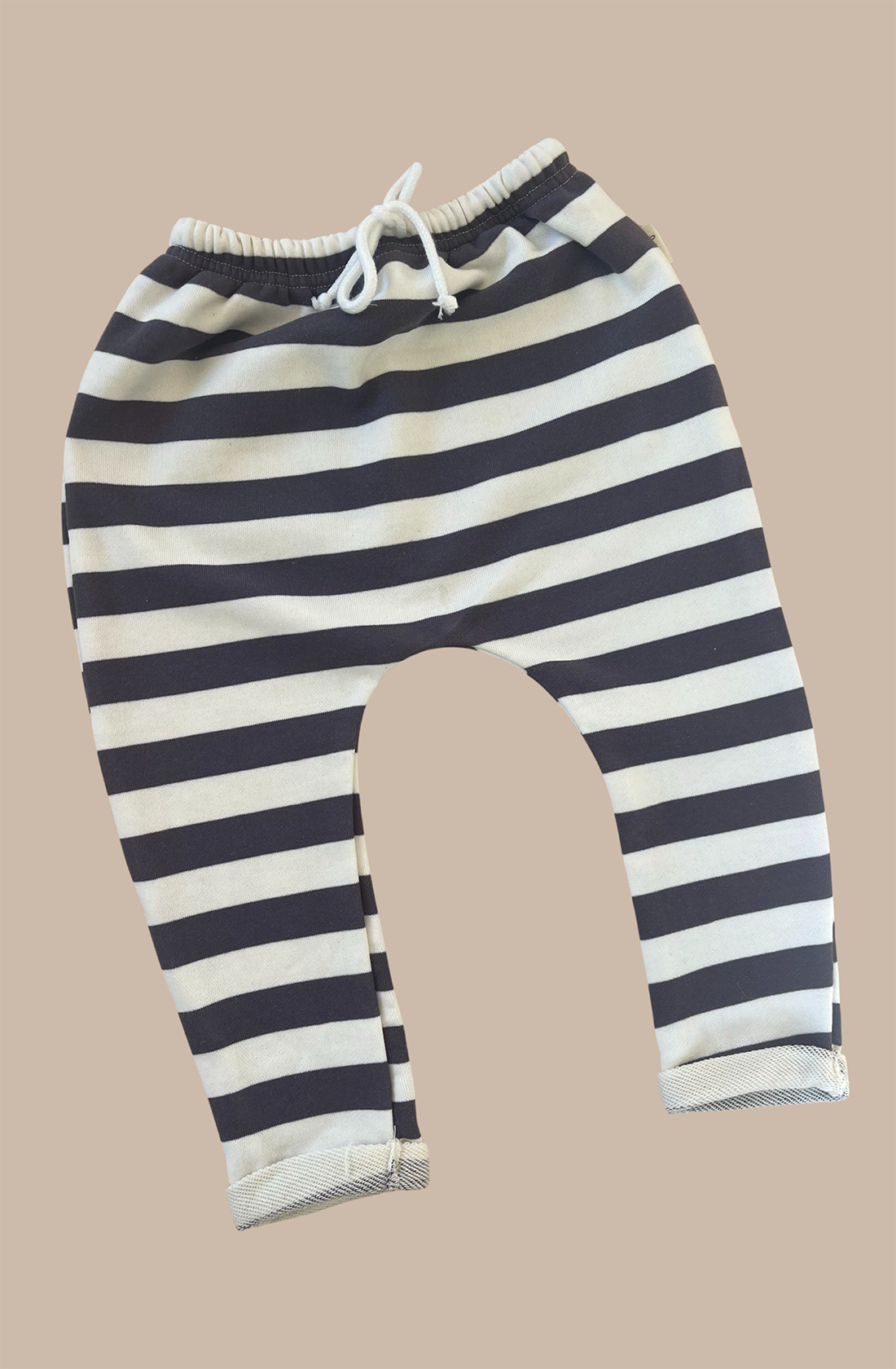 The sunny navy striped pants laid out on a brown background.