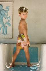 Boy turning to face the camera wearing printed shorts with a bare chest