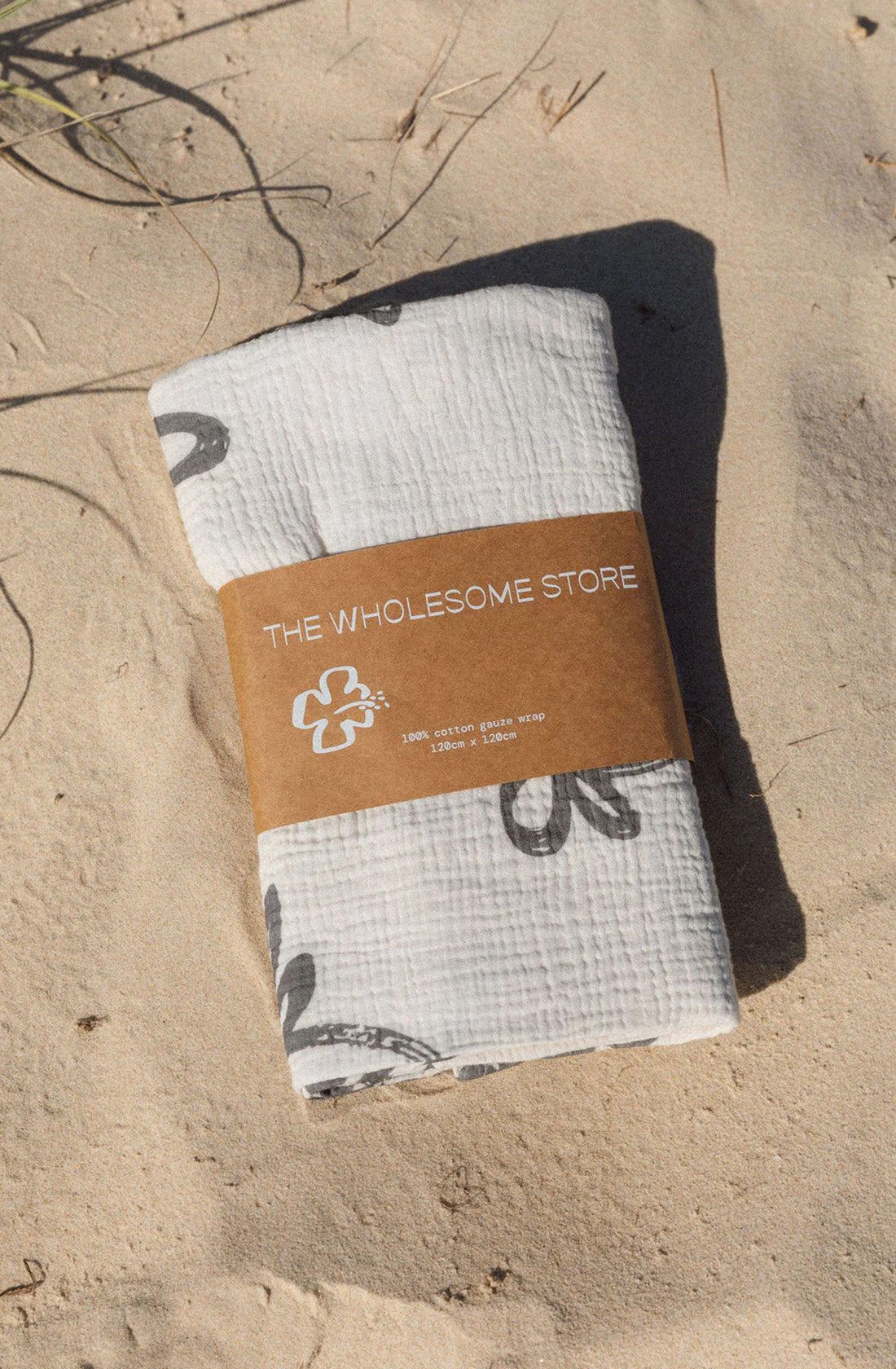 Flora swaddle wrapped in a kraft paper belly band lying on the sand at beach