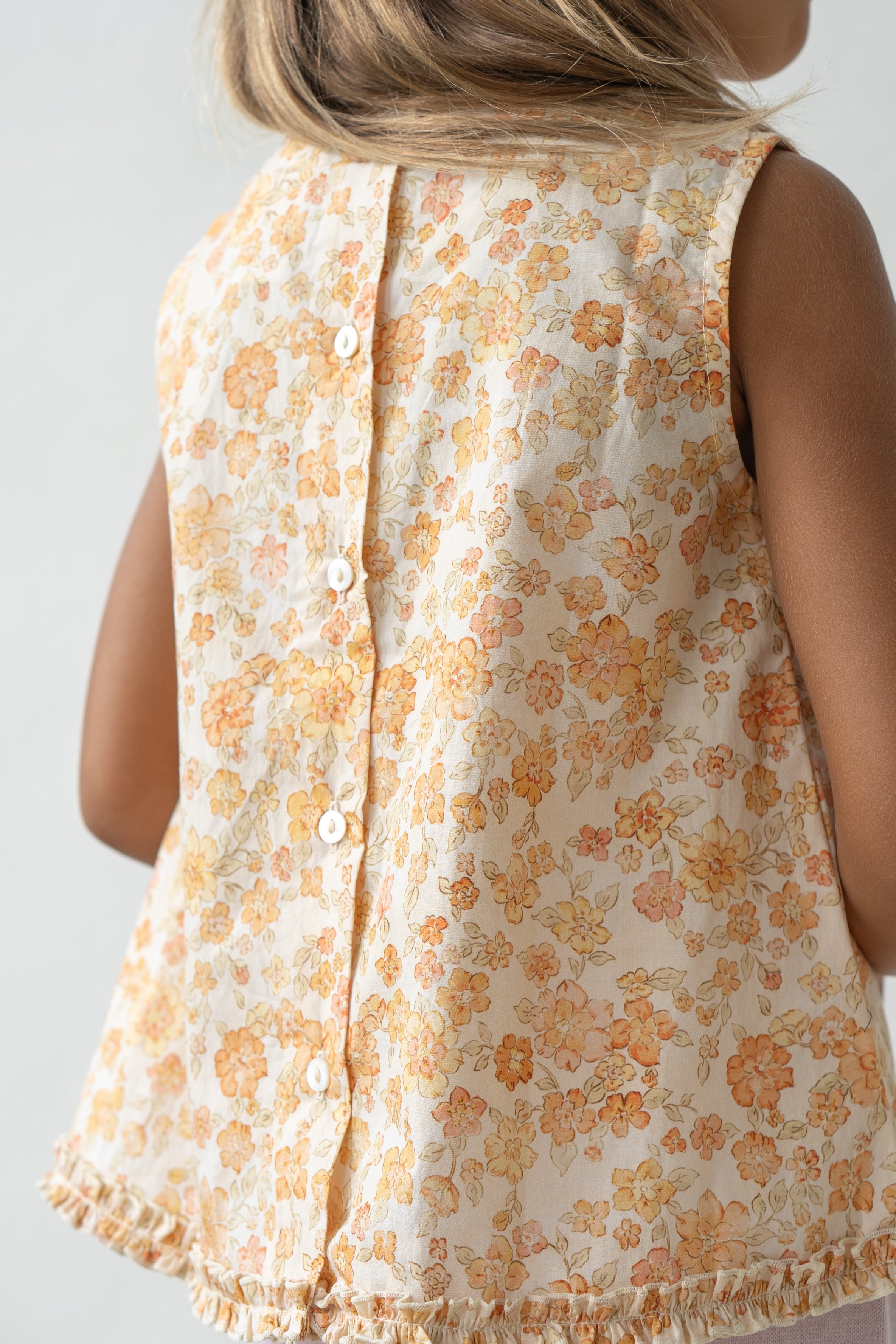 Young girl wearing the tilly blouse in buttercup from the back.