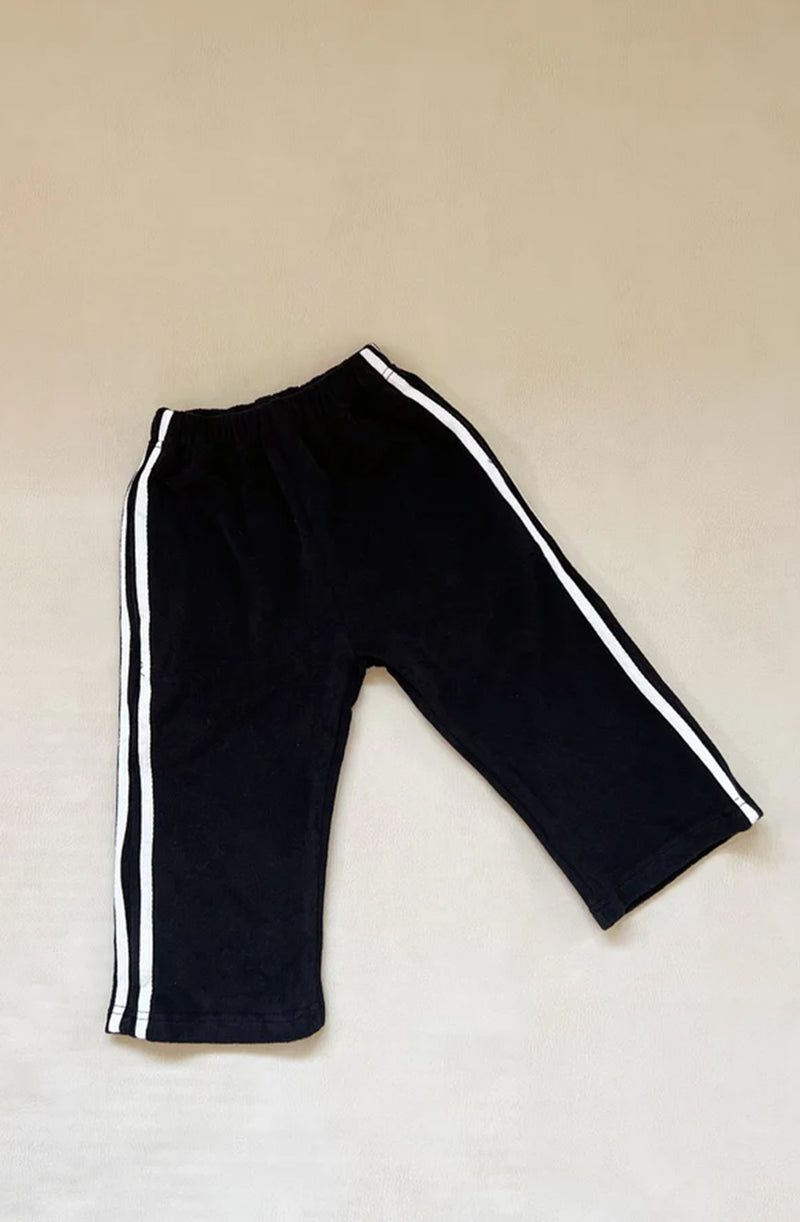 Black pants with white racer stripe flat laid on grey background