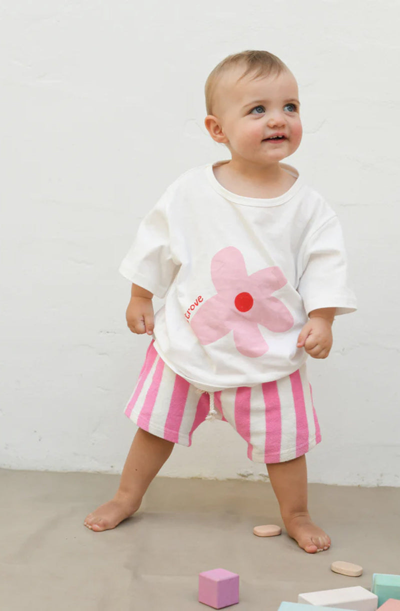 Baby girl wearing oversized white t-shirt with flower print and matching pink/white striped shorts