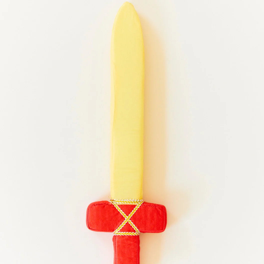 The Red Soft Sword by SARAH'S SILKS, featuring a yellow blade and a red handle decorated with yellow crisscross patterns, is showcased against a plain white background. Designed for pretend play, it provides young adventurers with an excellent opportunity to enhance their hand-eye coordination.