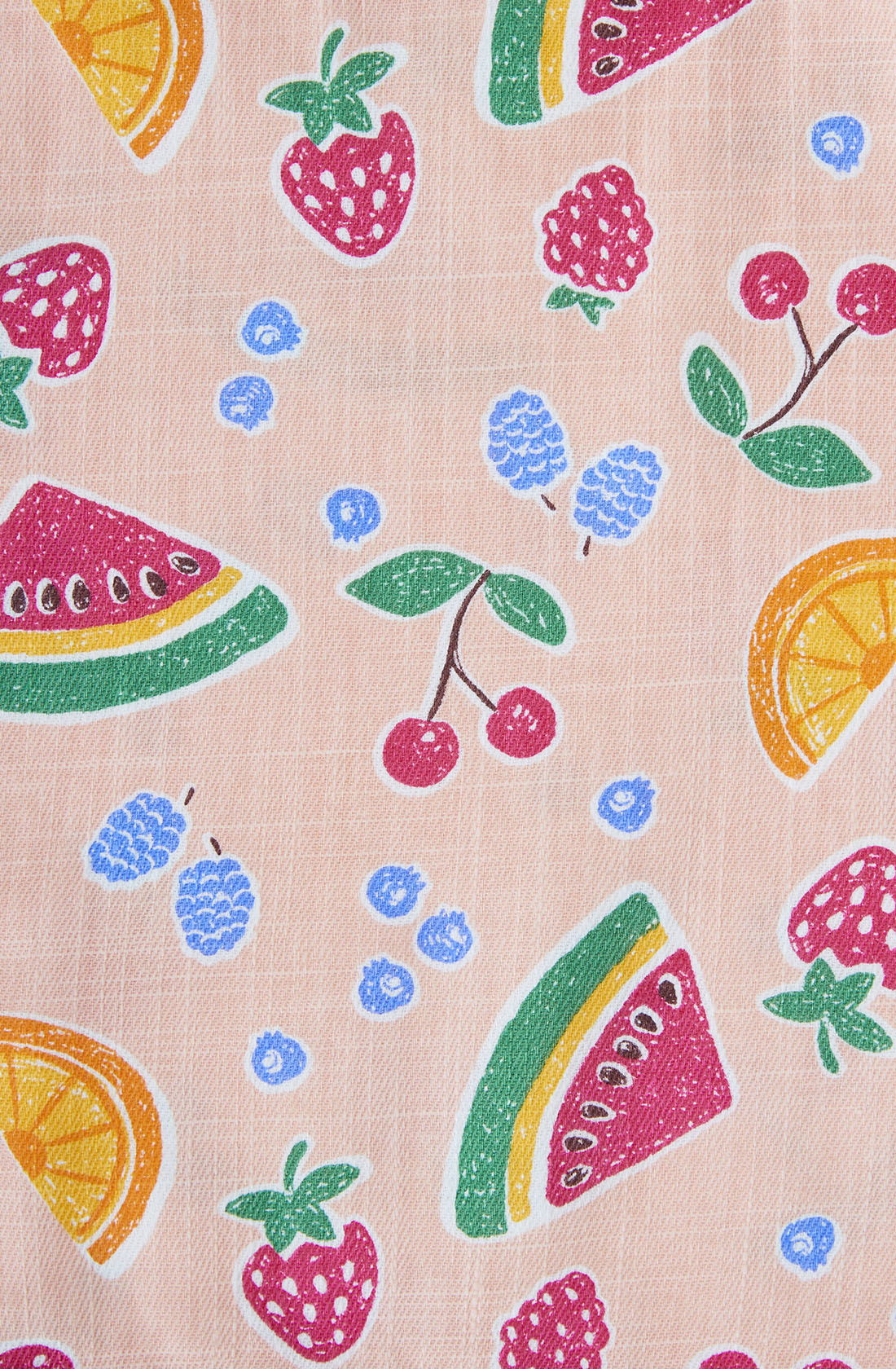 The Sara Linen Shortalls by GOLDIE + ACE showcase a playful and colorful pattern with hand-drawn illustrations of various fruits. The design features slices of watermelon and orange, alongside whole cherries, strawberries, raspberries, and scattered blueberries, all set against a pale pink background.