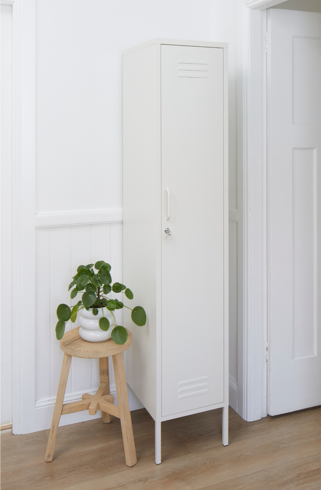 The skinny locker in white next to a pot plant.