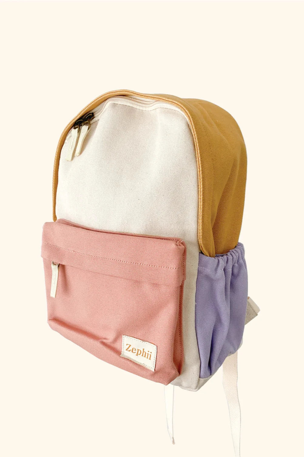 The Mimi Backpack by ZEPHII is a versatile accessory featuring a beige body, pink front pocket, lavender side pocket, and mustard top section. It includes a zipper closure and white adjustable straps. The bold colorway is complemented by the label "ZEPHII" on the front pocket.