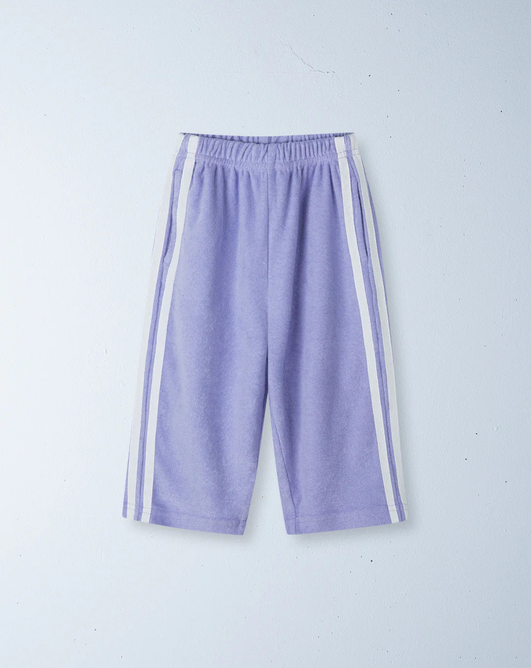 The Ziggy Zaza - Twin Stripe Terry Pant Lilac by ZIGGY ZAZA features light purple terry shorts with white vertical side stripes, an elastic waistband, and a relaxed fit. Made from 100% cotton terry, shown laid flat on a light background.