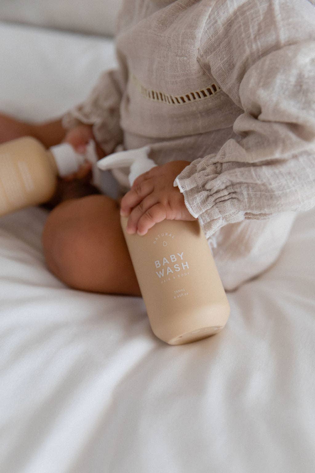 A baby holding Mama and Bird baby wash bottle and package.