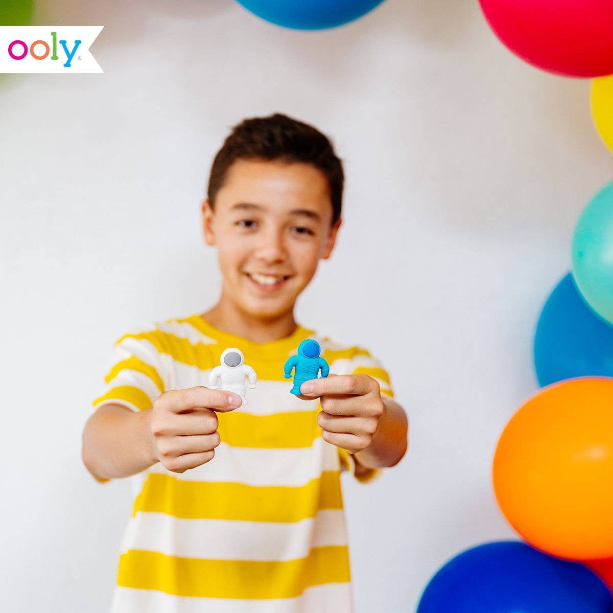 A young boy holding a white and blue astronaut erasers.