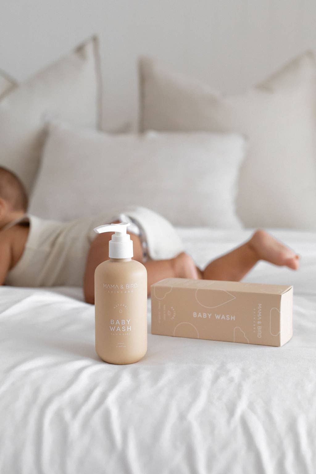 Mama and Bird baby wash bottle and package in front of a baby lying down.