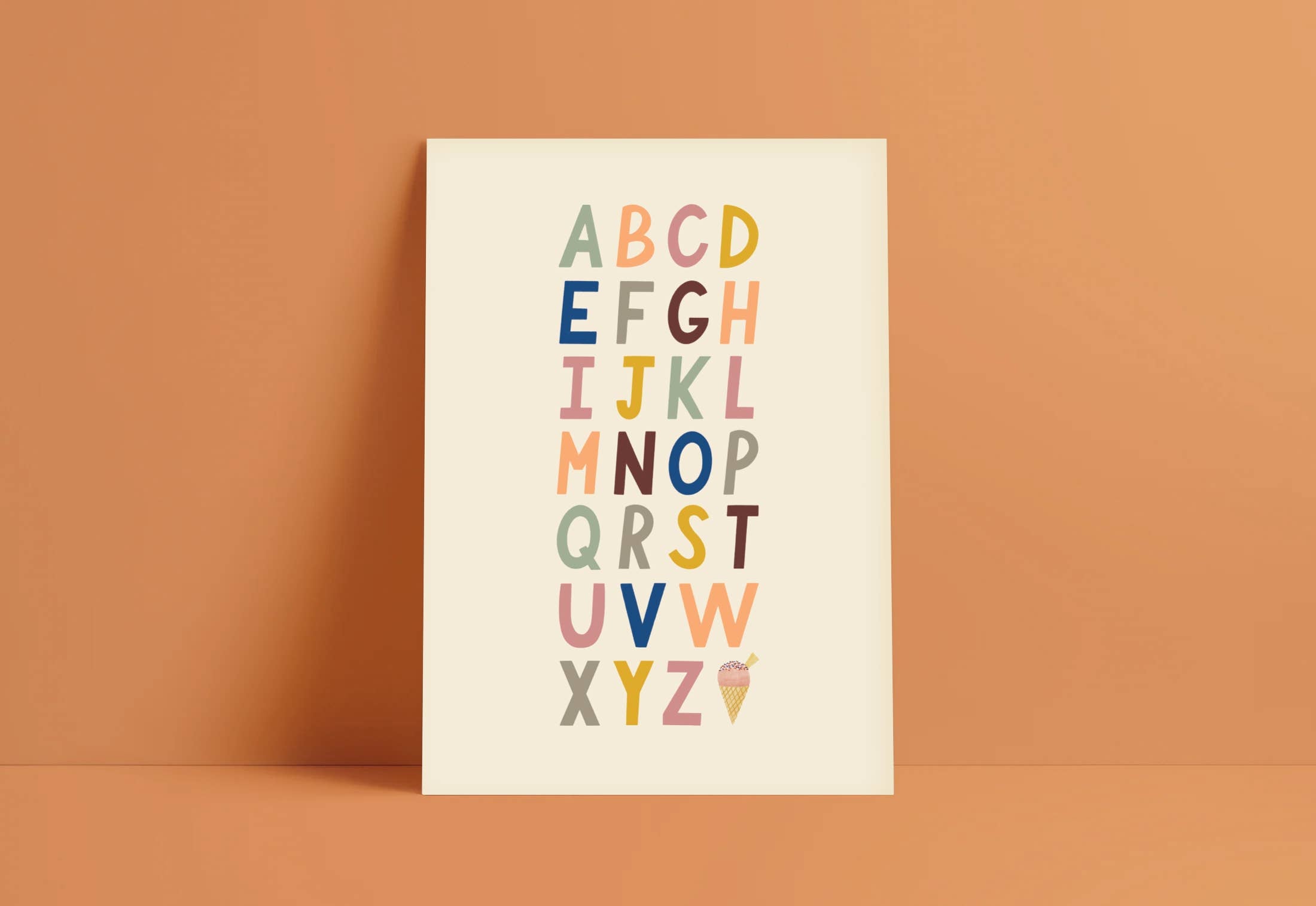 The Bold A-Z Alphabet Wall Art Print by LAUREN SISSONS STUDIO features a vibrant display of the English alphabet, with each letter in a different color. Arranged in seven rows on a cream backdrop, this educational artwork includes a small ice cream cone graphic for the letter "I". Perfect as nursery decor, it is set against an orange background.