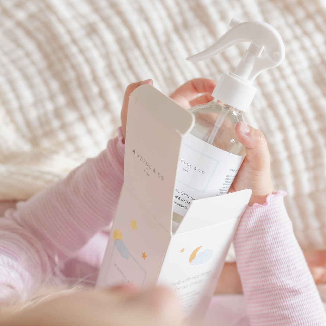 Mindful & Co Magnesium spray bottle inside its packaging being taken out by a small kid.