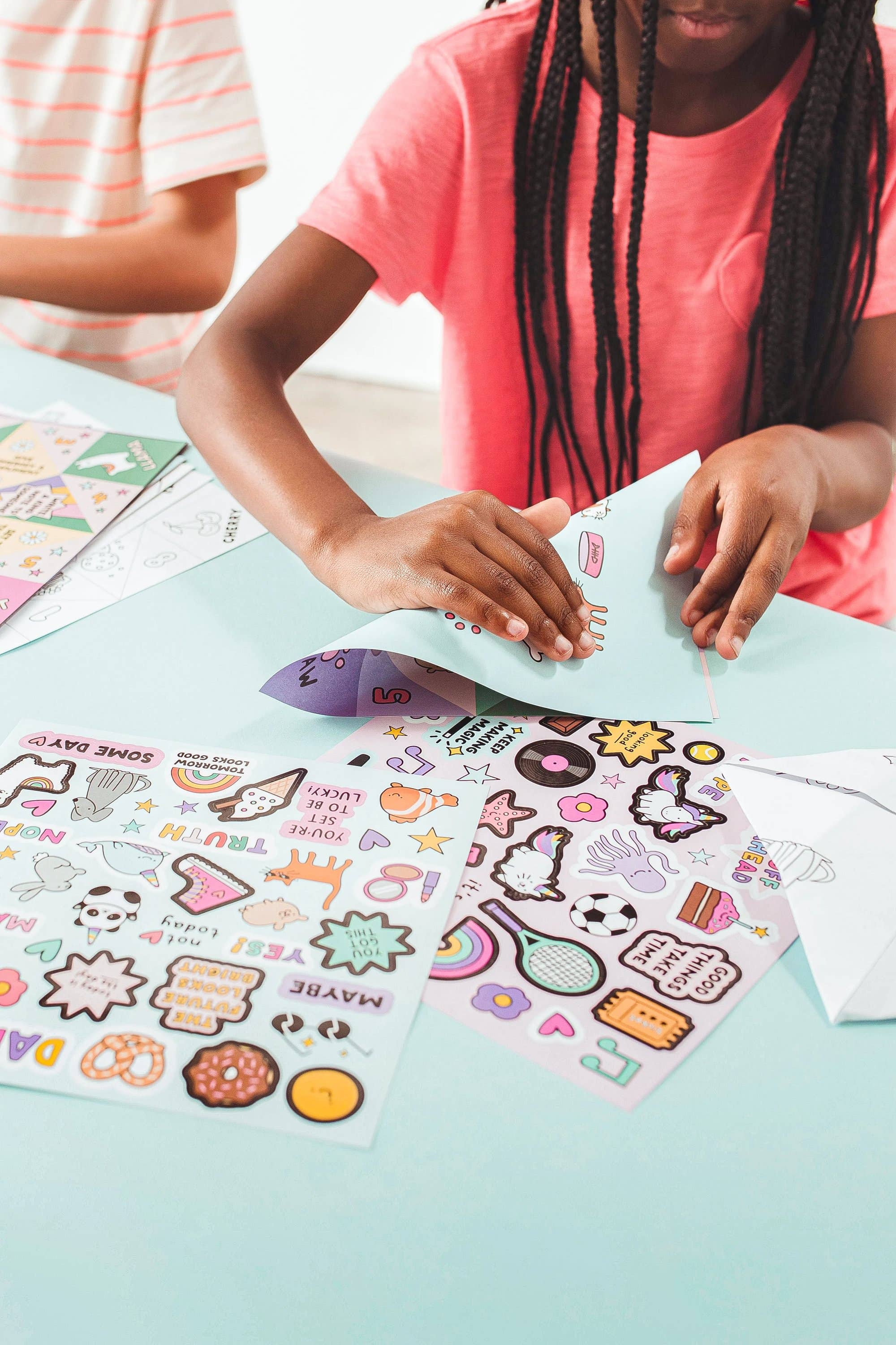 A young girl folding a piece of paper in half.