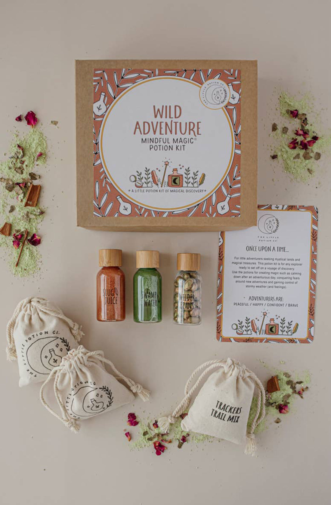 A "Wild Adventure MINDFUL Potion Kit" by THE LITTLE POTION CO is showcased, featuring miniature bottles labeled "Luck Juice," "Nature's Nectar," and a third filled with green liquid, along with sachets labeled "Potion of Peace" and "Tracker's Trail Mix." This magical potion kit also includes an instruction card.