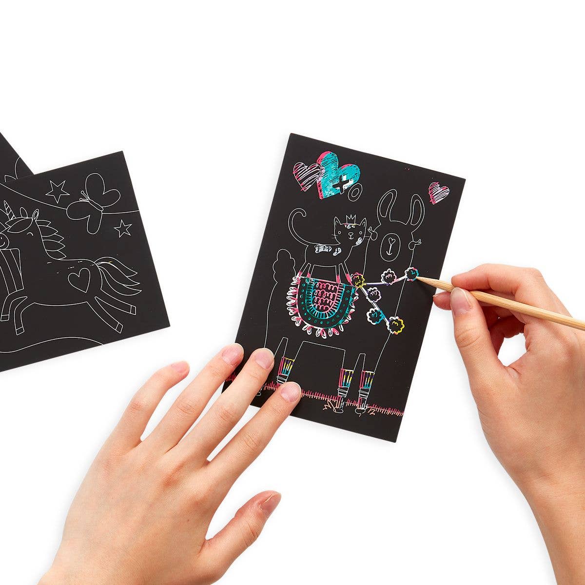 A person colouring in a picture on black piece of paper.