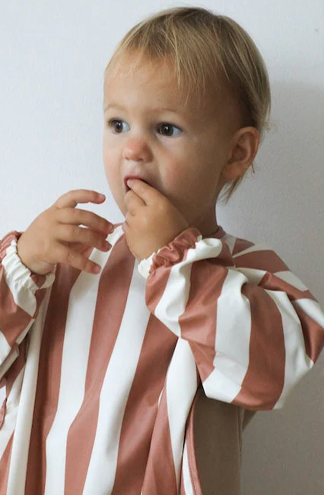 Young boy wearing ROMMER Smock Bib in Cinnamon Stripe.