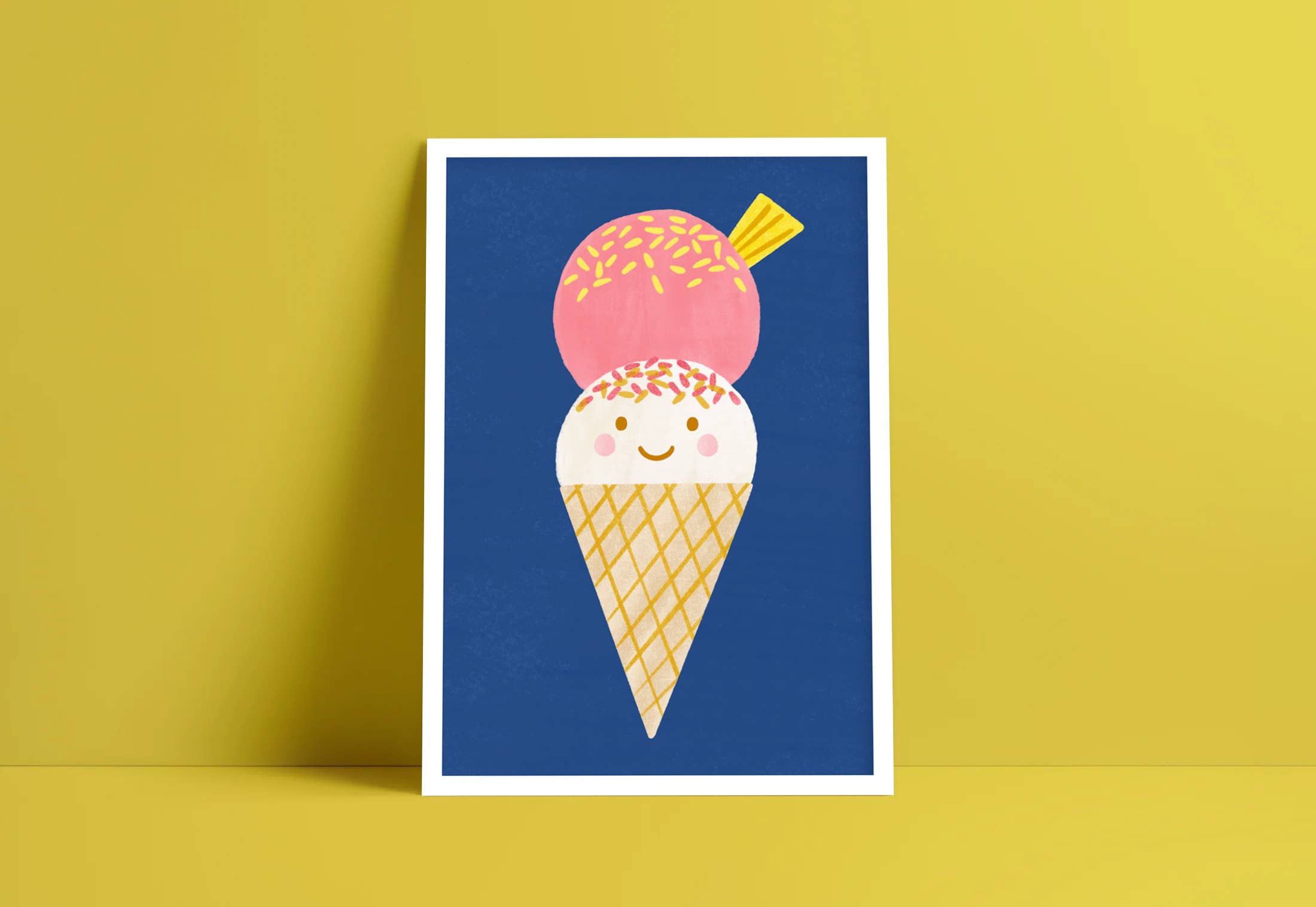 The Ice Cream Wall Art Print by LAUREN SISSONS STUDIO is an illustrated poster, printed on high-quality art paper, depicting an ice cream cone with two scoops. The pink scoop is adorned with sprinkles while the white scoop has a smiling face and additional sprinkles on top. This contemporary artwork pops against a blue background and yellow wall, creating a cheerful display.