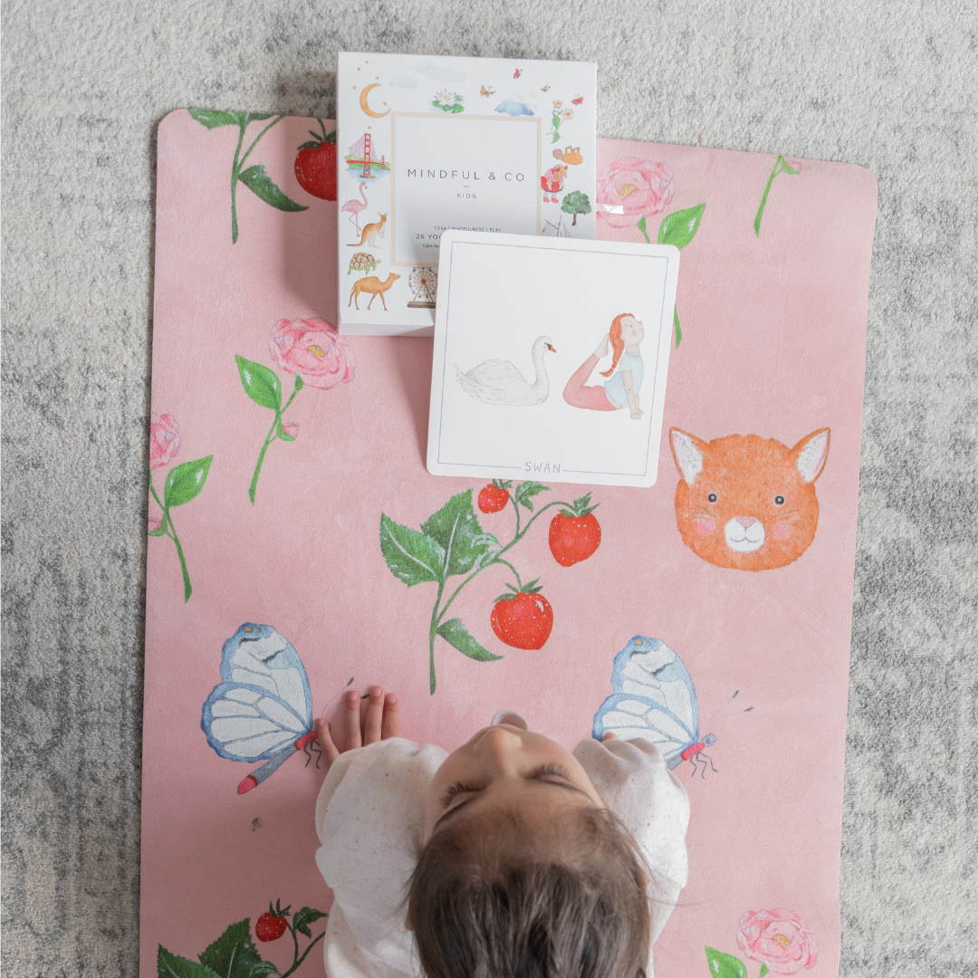 A young girl on the sweet themed pink kids yoga mat with mindful cards.