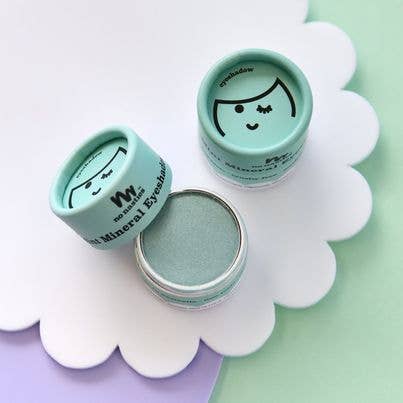 Three containers of the Kids Eco Natural Pressed Eyeshadow & Blush by no nasties kids are displayed on a white and pastel green background. Two containers feature closed illustrated lids, while one is open, showcasing the mint-colored eyeshadow inside. Crafted with natural ingredients, they provide a hypoallergenic experience.