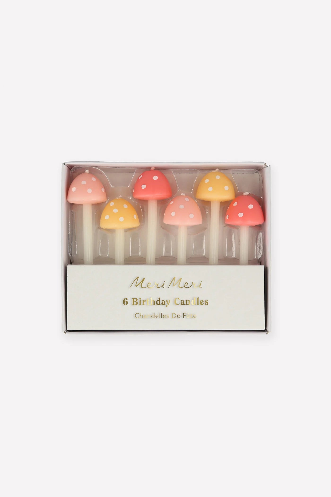 Package of six MERI MERI Mushroom Birthday Candles, available in two sizes and featuring enchanting pastel shades of red, pink, and yellow with delightful white spots. Ideal for adding a whimsical touch to a garden party celebration.