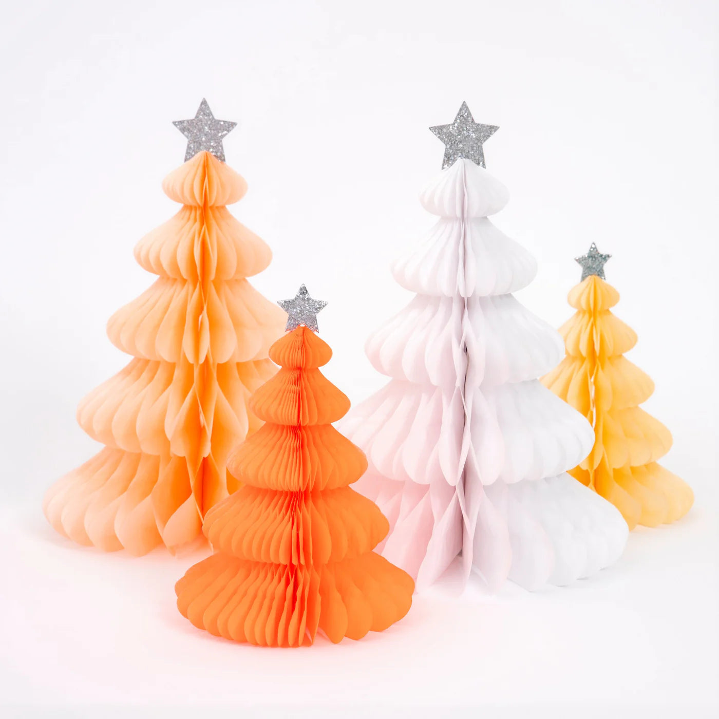 The Rainbow Forest Honeycomb Decorations by MERI MERI feature a delightful set of four honeycomb trees in vibrant orange, white, and yellow hues. Crafted from tissue paper and topped with eco-friendly glitter stars, these decorations create a festive and whimsical appearance on the white background.