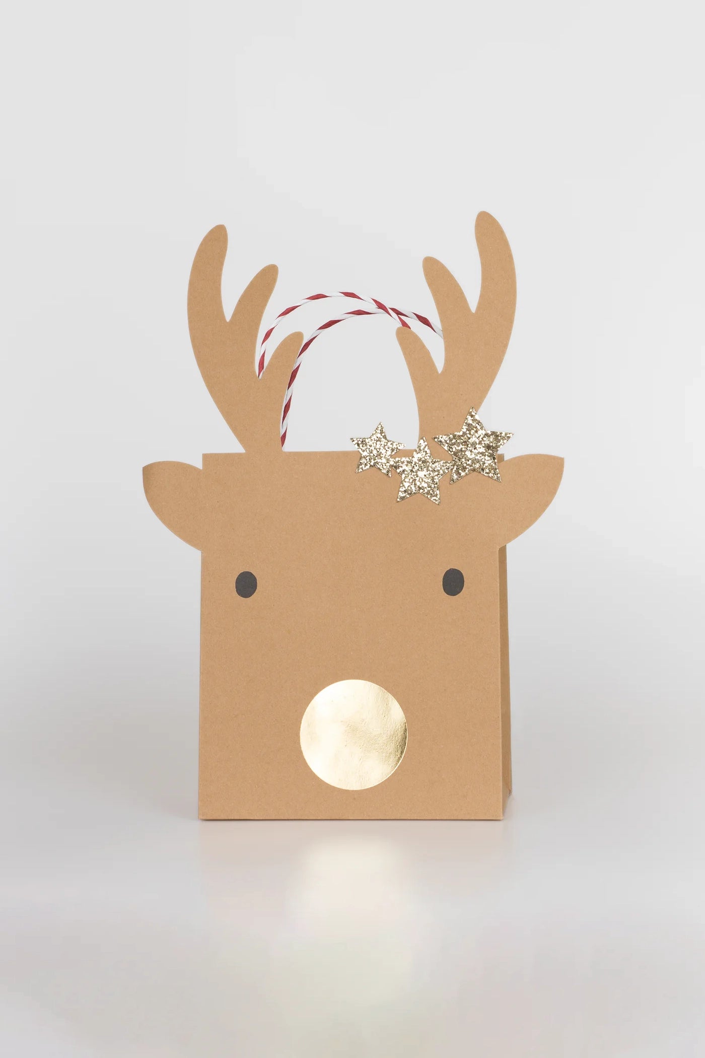 Celebrate the holiday season with festive flair using the MERI MERI Medium Reindeer With Stars Gift Bags (Pack of 2). These charming gift bags showcase a reindeer design complete with antlers, a round shiny gold nose, and are decorated with three gold star-shaped ornaments on one of the antlers. The bag also features a red and white striped handle for added holiday charm.