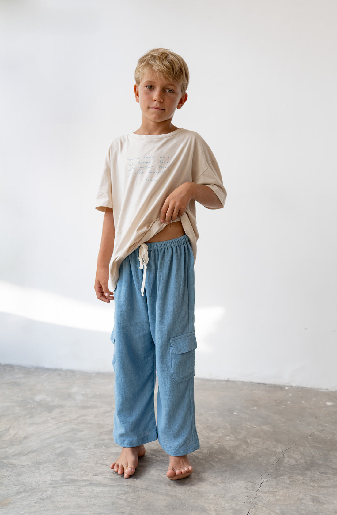 Young boy wearing the henna pants in cornflower and beige t shirt.