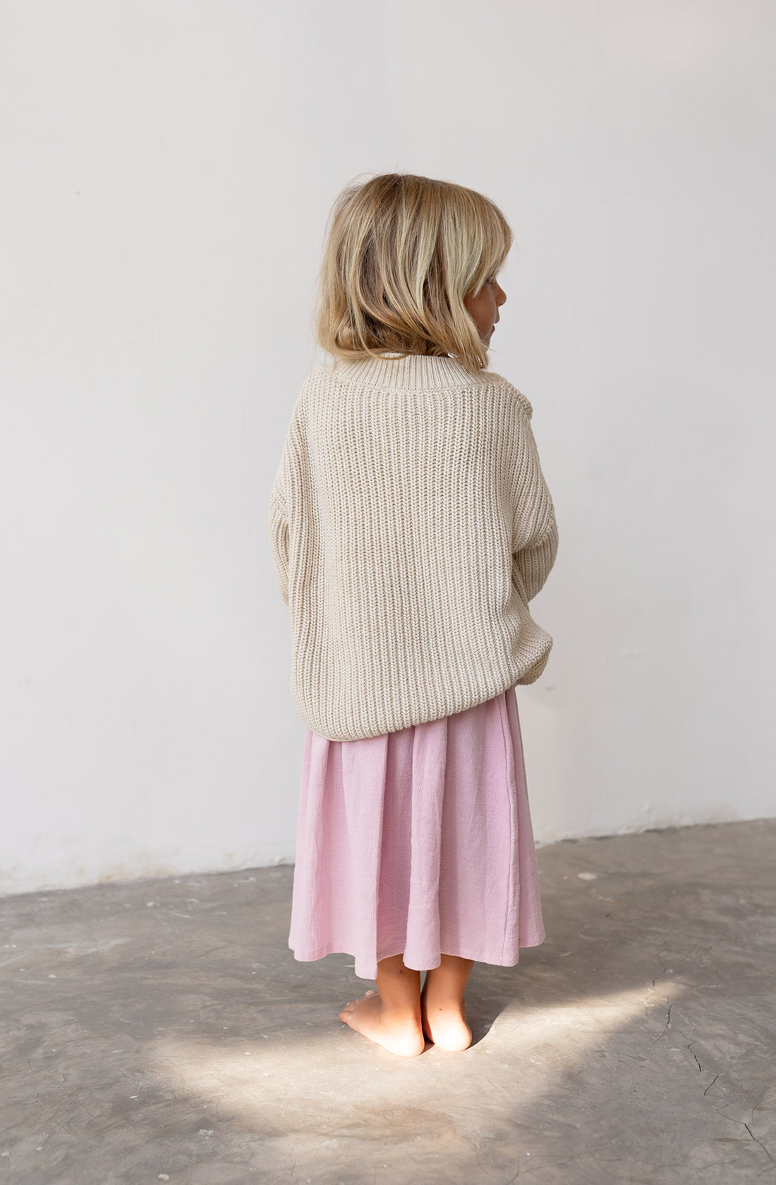 Back view of a young girl wearing the chunky knit jumper in natural.