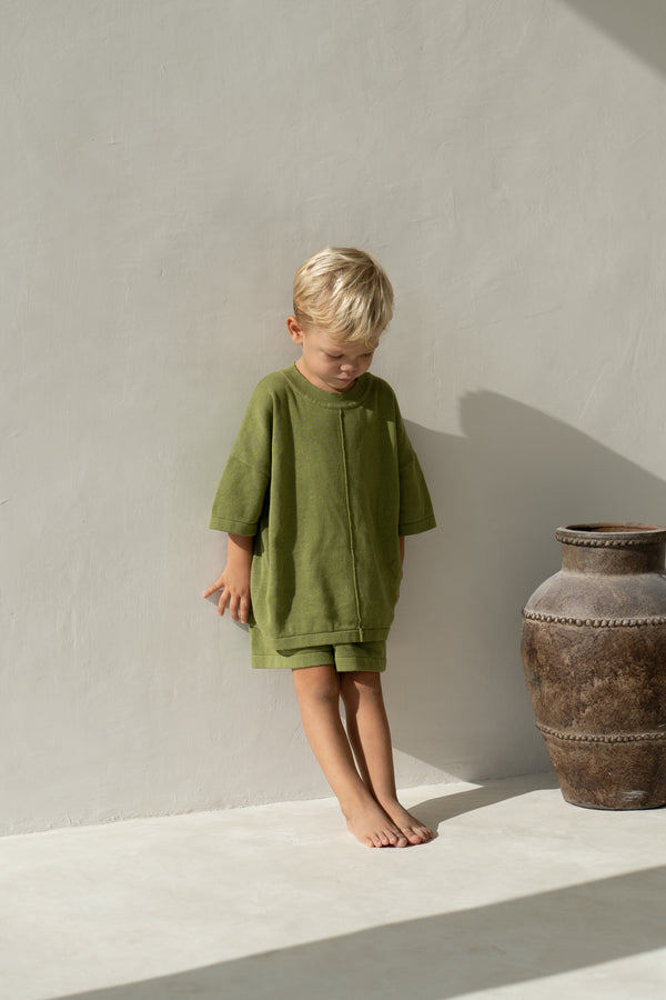 Blonde toddler boy wearing olive knit tee and shorts