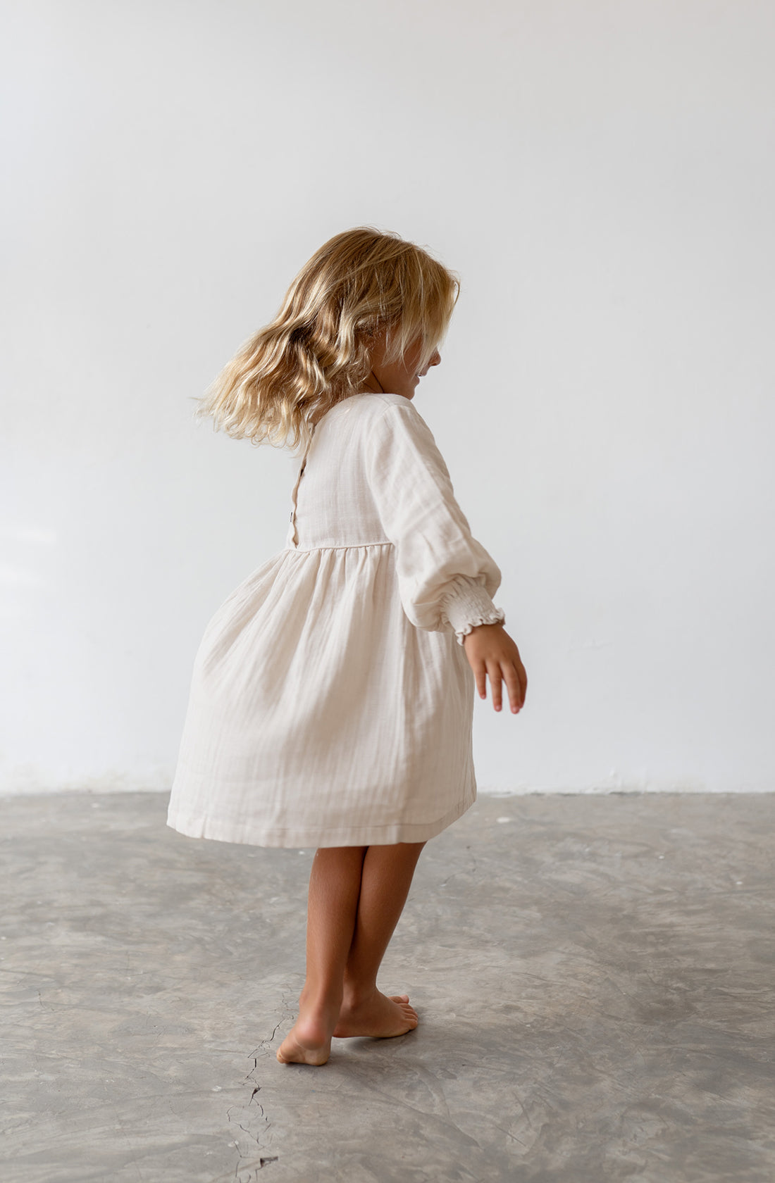 Young girl wearing the yumi dress in natural.