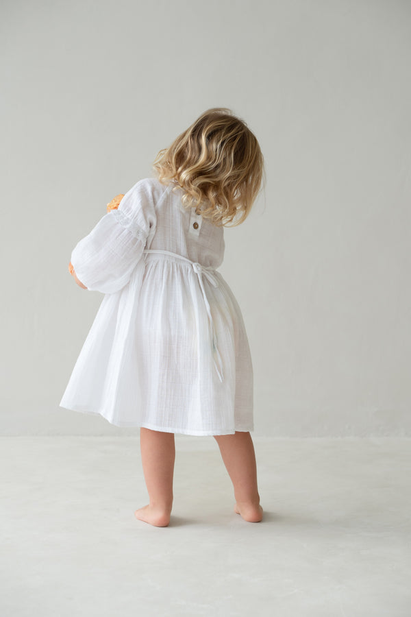 Back of blonde toddler girl wearing white Maggie dress