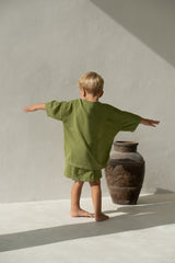 Back of blonde toddler boy wearing knit tee and short set in olive