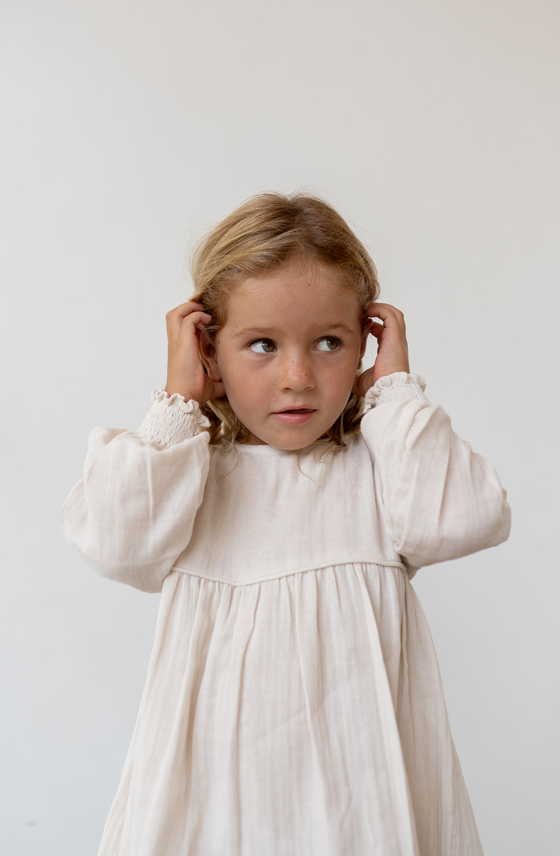 Young girl wearing the yumi dress in natural.