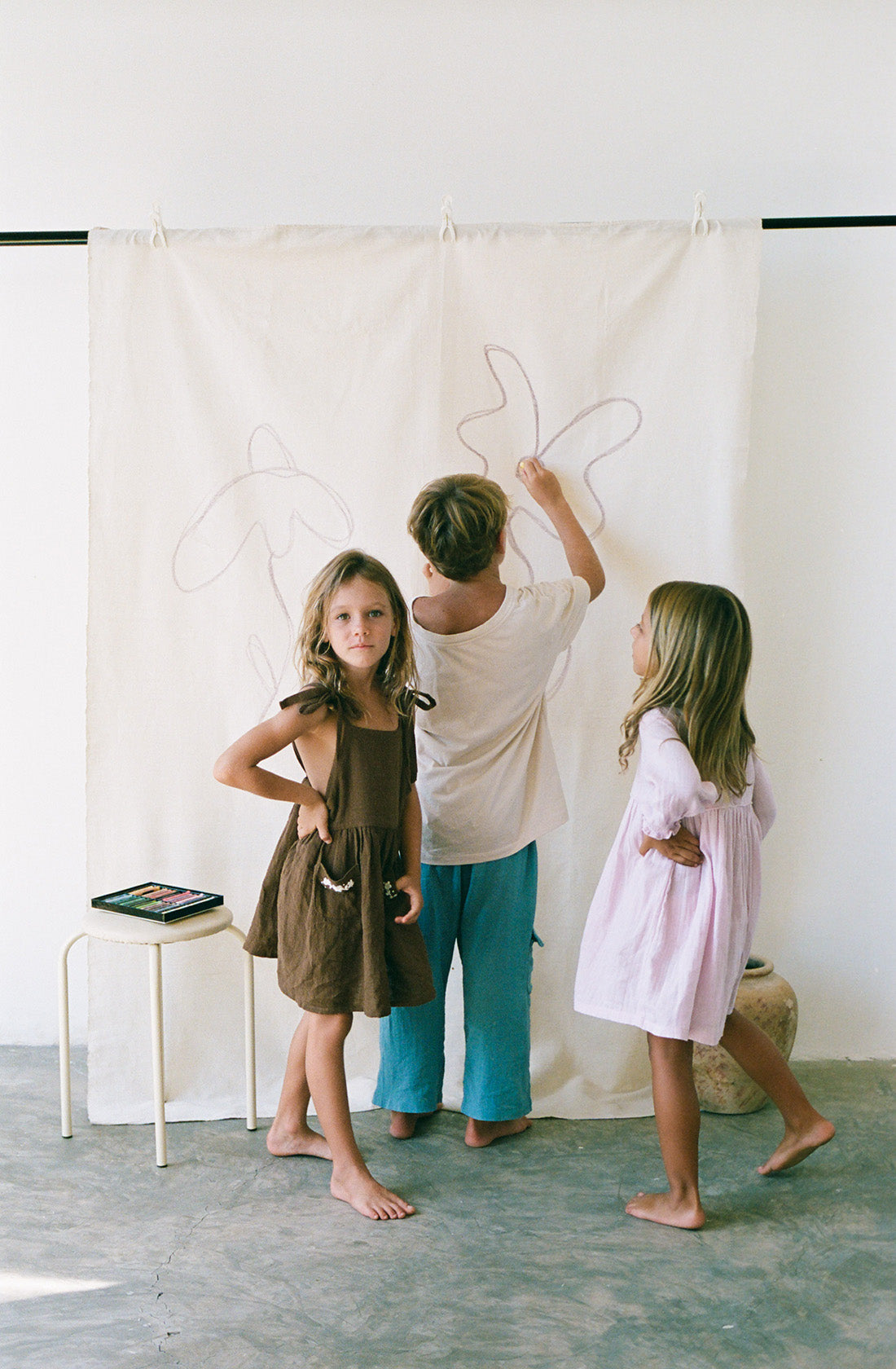 Young girl wearing the luna pinafore in cocoa.