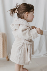 Toddler dressed in bath robe holding her parent's hand