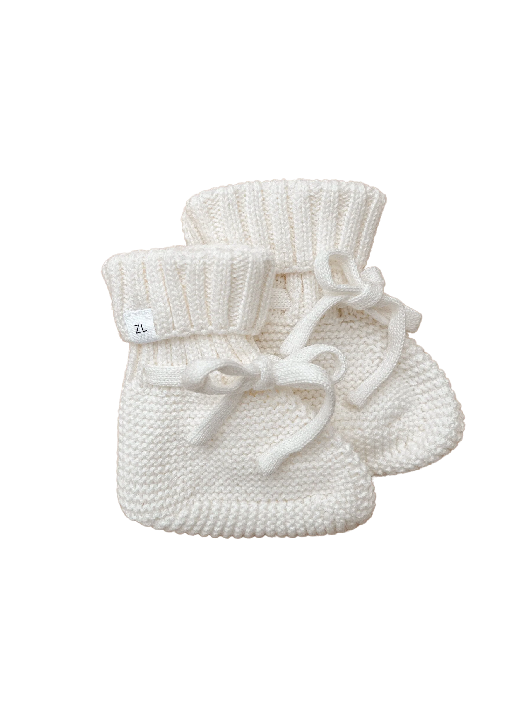 The Ziggy Lou - Booties Milk by ZIGGY LOU are white knit booties with ribbed cuffs and tied laces, shown against a black background.