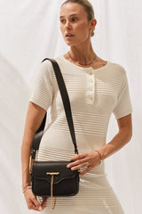 Close up of woman wearing Isabella Dress in Off White with black handbag.