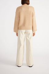 Rear view of woman wearing Ana Oversized Jumper with cream wide leg jeans.